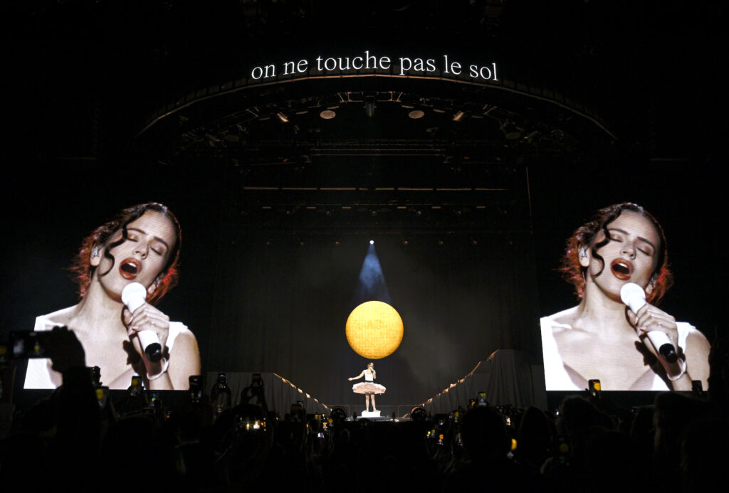 Rosalía cantando en directo con un gran sol de fondo en el escenario del LUX Tour detalle de la actuación de Rosalía en Lyon con estética visual marcada por un sol central