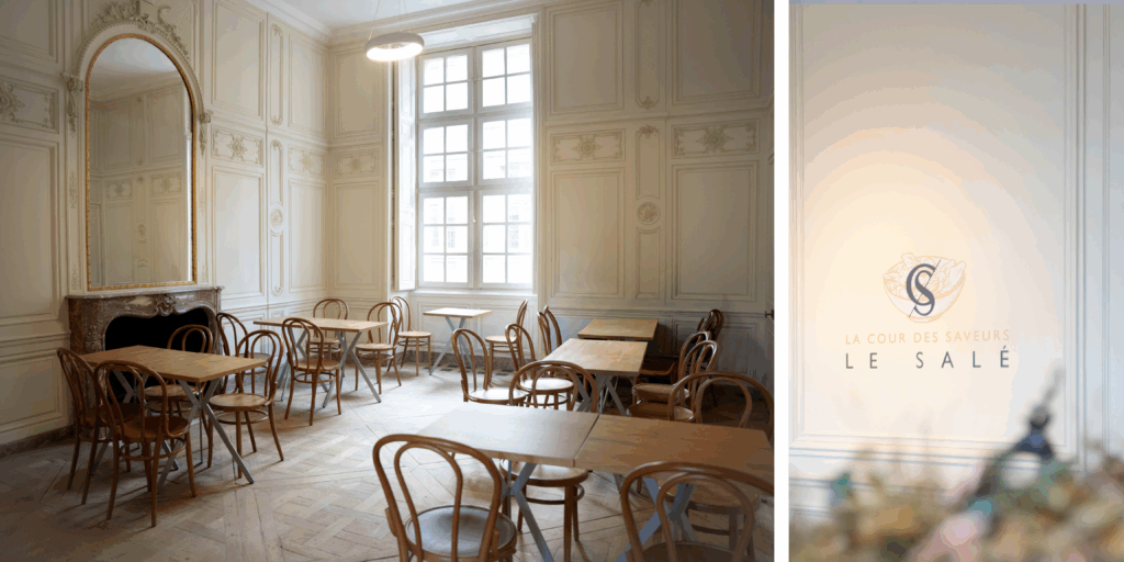 Interior de La Cour des Saveurs en el Château de Versailles con mostradores gastronómicos franceses y visitantes degustando productos gourmet