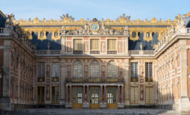 Interior de La Cour des Saveurs en el Château de Versailles con mostradores gastronómicos franceses y visitantes degustando productos gourmet